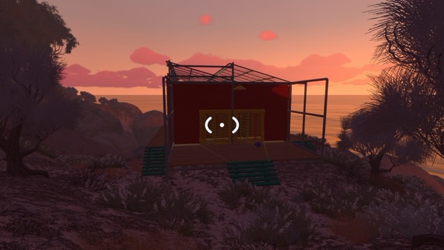 A small red puzzle house with a yellow front panel on a ledge above the sea