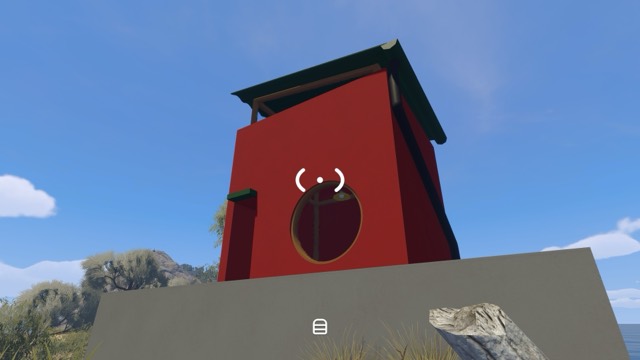 A red Patience puzzle structure stands on a cliff overlooking the water
